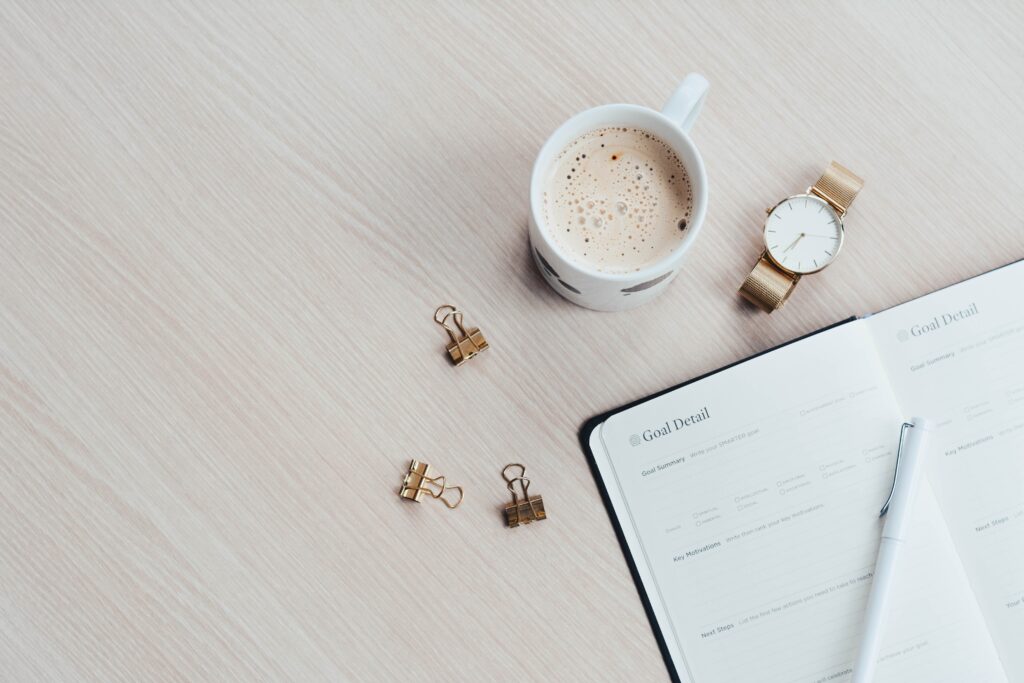 desk with coffee mug and weekly planner laying on top