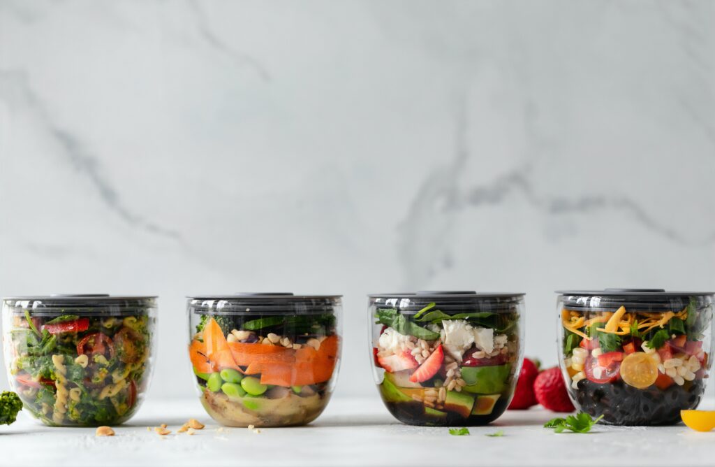 four Tupperware containers showing heathy meals inside.